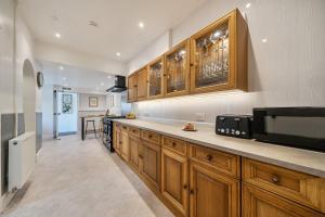 a kitchen with wooden cabinets and a microwave at Clarence House in Llandudno