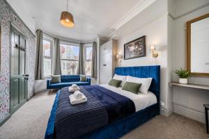 a bedroom with a blue and white bed and windows at Clarence House in Llandudno