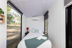 a bedroom in a house with a large window at Kenny and Clancy's Camp by Tiny Away in Grandchester