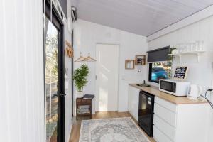 a small kitchen with a desk with a microwave and a tv at Kenny and Clancy's Camp by Tiny Away in Grandchester +24 photos