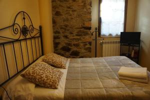 a bedroom with a bed with pillows and a stone wall at Casa Morrosco in Molinaseca
