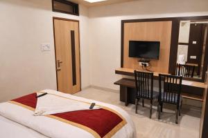 a hotel room with a bed and a desk and a television at Hotel Benaras Gharana Inn in Varanasi