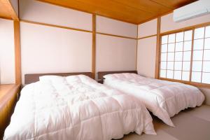 two beds in a room with two windows at rinne 北軽井沢 Forest2 in Tsumagoi