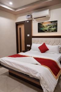 a bedroom with a large white bed with red pillows at Hotel Benaras Gharana Inn in Varanasi