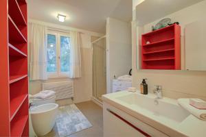 a bathroom with a sink and a toilet and red shelves at Torbole Lake Front - Happy Rentals in Arco