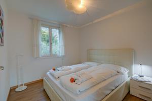 a white bedroom with a large bed with white sheets at Torbole Lake Front - Happy Rentals in Arco