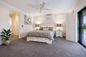 a white bedroom with a bed and a ceiling fan at Magic on MacArthur - Modern 4BR Home in Annandale in Rosslea