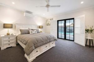 a white bedroom with a large bed and a window at Magic on MacArthur - Modern 4BR Home in Annandale in Rosslea