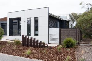 a white house with a fence in front of it at The Retreat Inverloch in Inverloch