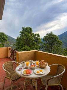 a table with breakfast foods and drinks on a balcony at Wild Meadows by Levitate - Exclusive Dual Bedroom Chalet Open Sky View & Fully Equipped Kitchen in Rāmgarh