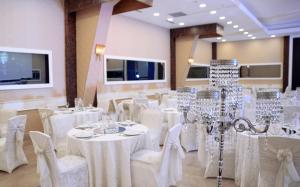 a banquet hall with white tables and chairs and chandeliers at Esila Hotel in Ankara