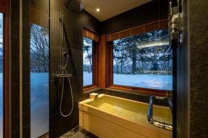 a bathroom with a tub and a shower and a window at Kogetsu To 湖月燈 in Lake Toya