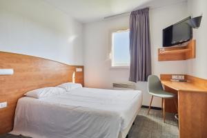 a bedroom with a bed and a desk and a television at CIT'HOTEL Armony Hotel in Bourg-Achard