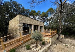 a stone house with a wooden deck in the woods at Maison Terre de Lune in Mondragon