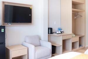 a living room with a chair and a flat screen tv at OnsenHouse Boutique Stay - Căn hộ gần biển Mỹ Khê in Danang