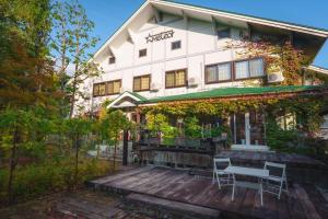 a building with a table and chairs on a wooden deck at Hakuba Pension & Log Hotel Meteor in Hakuba