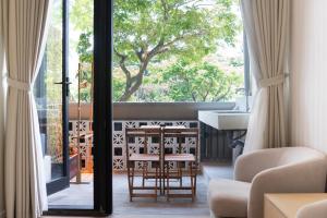 a living room with a window and a table and chairs at OnsenHouse Boutique Stay - Căn hộ gần biển Mỹ Khê in Danang