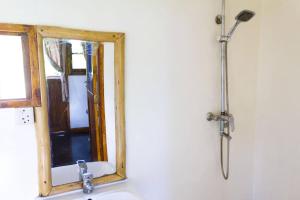 a bathroom with a shower and a mirror over a sink at Mbao Boutique Bungalows in Jambiani +19 photos