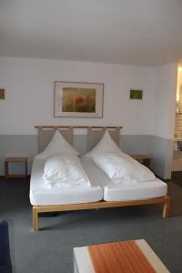 a bed with white pillows on it in a room at RB Hotel Linde in Wangen