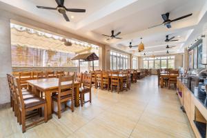 a restaurant with wooden tables and chairs and windows at Sunday Lotus Garden Resort By The Sea Mui Ne in Mui Ne