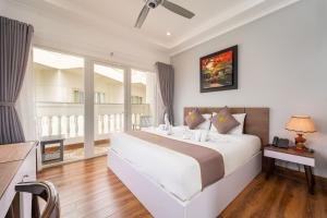 a bedroom with a large white bed and a window at Sunday Lotus Garden Resort By The Sea Mui Ne in Mui Ne