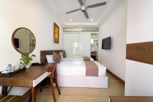 a bedroom with a bed and a desk and a mirror at Sunday Lotus Garden Resort By The Sea Mui Ne in Mui Ne