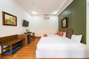 a hotel room with two beds and a desk at Sunday Lotus Garden Resort By The Sea Mui Ne in Mui Ne
