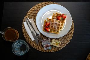 a plate of waffles and strawberries on a table at Hang The Hat House in Valmiera