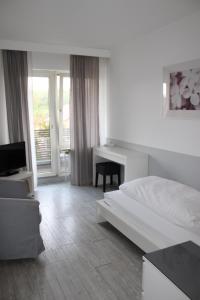 a white bedroom with a bed and a desk at RB Hotel Linde in Wangen