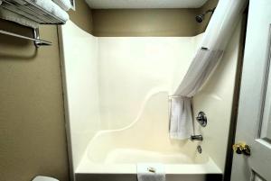 a white bathroom with a tub and a toilet at Super 8 by Wyndham Booneville in Booneville +31 photos