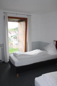 two beds in a room with a window at RB Hotel Linde in Wangen +1 photo