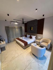 a bedroom with a bed and a couch and a chair at Kaveri Pool Pavilion in Paravūr