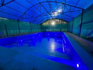 a swimming pool with blue lights in a building at Infinity Farm Grove in Olavakod Junction