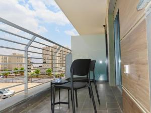 a black chair on a balcony with a view of a city at דיויד רזידנט & ספא - by Desert 360 Mountain & sea view in Eilat