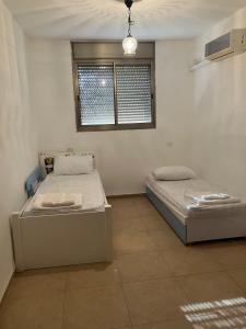 two beds in a room with a window at קסם המעיינות in Bet Sheʼan