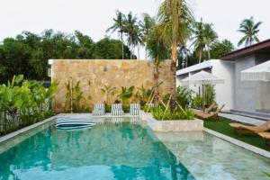 a swimming pool with chairs and a house at Bilha 1 BR Deluxe Suite Room in Kuta Lombok