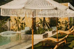 a large straw umbrella sitting next to a pool at Bilha 1 BR Deluxe Suite Room in Kuta Lombok