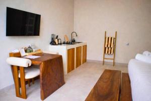 a living room with a table and a kitchen with a television at Bilha 1 BR Deluxe Suite Room in Kuta Lombok
