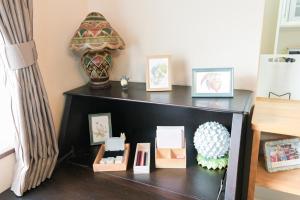 a black shelf with pictures and a vase on it at 民泊 丘の上 in Seto