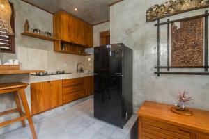 a kitchen with a black refrigerator and wooden cabinets at Bara Villa by GenuineHost in Tegalalang