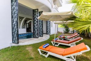 a villa with a swimming pool and two lounge chairs and an umbrella at Aara-boutique stay udaipur in Udaipur