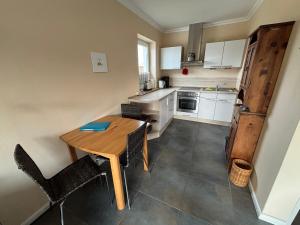 a small kitchen with a wooden table and chairs at Leuchtturm 1 in Fehmarn