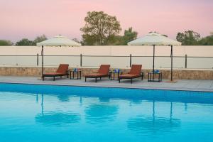 a pool with chairs and tables and umbrellas at Serenity Hill Resort Near 2Km Fateh Sagar Lake Udaipur in Udaipur