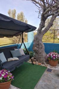 a black couch under a black umbrella next to a tree at Bluefullstop-Μπλε Τελεία in Artemida