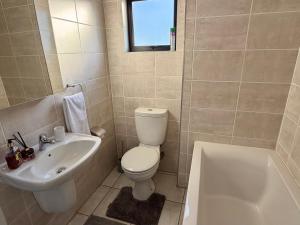 a bathroom with a toilet and a sink and a tub at Charming Oasis in the East in Boksburg +21 photos