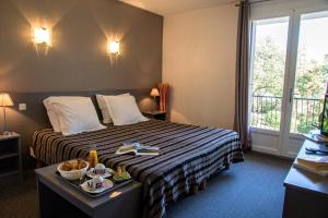 Una habitación de hotel con una cama con una bandeja de comida. en Hôtel Les Persèdes, en Lavilledieu