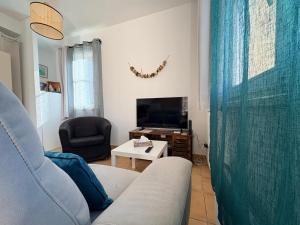 a living room with a couch and a tv at Appartement familial centre et plage in Soulac-sur-Mer