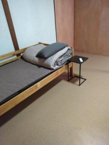 a bed with a wooden frame and a pile of clothes at OKAYAMA Backpackers in Okayama +7 photos