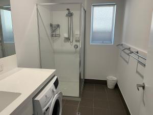 a bathroom with a shower and a washing machine at Jurien Beachfront Chalets in Jurien Bay +22 photos