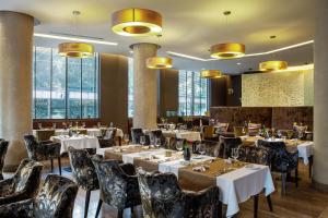 ein Restaurant mit Tischen und Stühlen und großen Fenstern in der Unterkunft DoubleTree by Hilton Bratislava in Bratislava + 70 Fotos